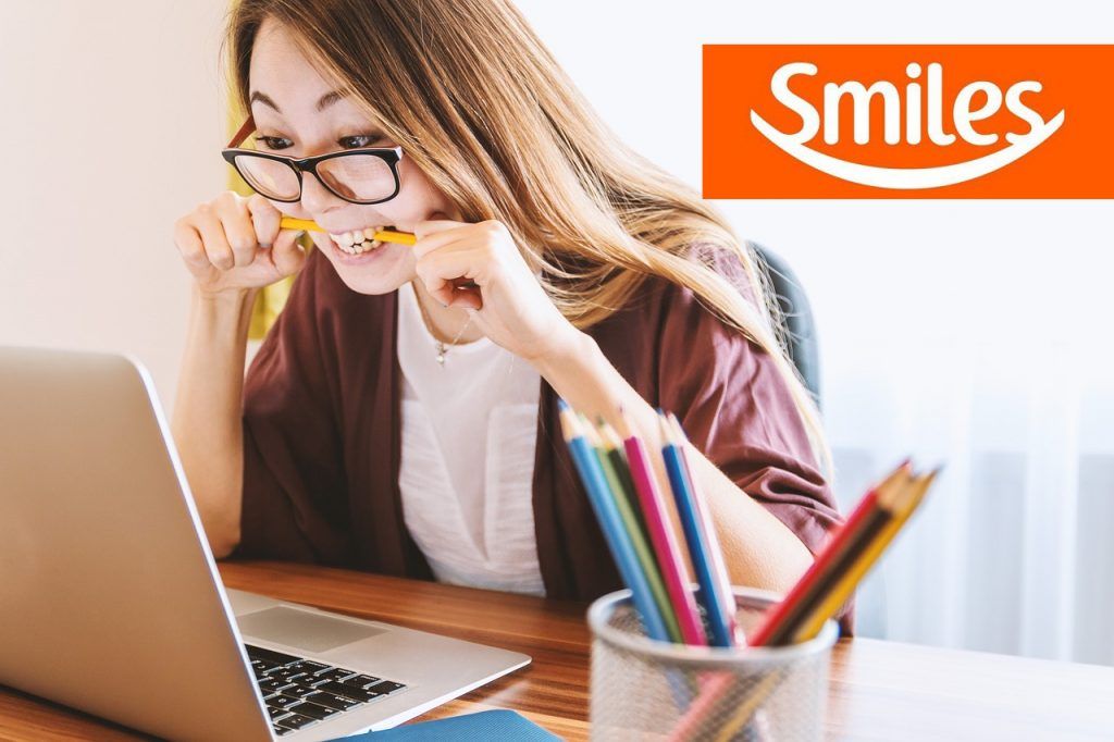 mujer frente a una laptop y el logo de smiles argentina arriba a la derecha