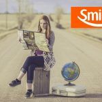 una mujer en una ruta mirando un mapa. Arriba a la derecha, el logo de Smiles Argentina