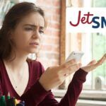 mujer ofuscada mirando el teléfono junto a un logo de jetsmart